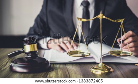 Judge gavel with Justice lawyers, Gavel on wooden table and Counselor or Male lawyer working on a documents. Legal law, advice and justice concept.