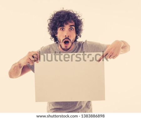 Funny and attractive millennial man showing blank poster with copy space for text looking excited as it shows a great product or amazing sale or great advertisement. studio shot. Marketing concept.