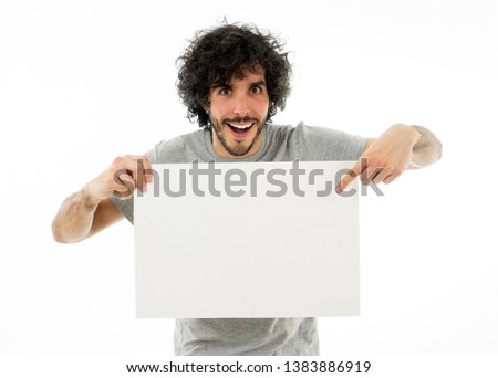 Funny and attractive millennial man showing blank poster with copy space for text looking excited as it shows a great product or amazing sale or great advertisement. studio shot. Marketing concept.