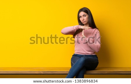 Young woman sitting on table making time out gesture