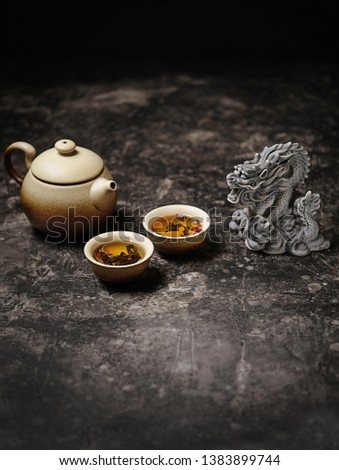 Beautiful dragon figurine, clay teapot and cups close up on dark table background. Asian culture cuisine concept. tea ceremony in Japanese or chinese style
