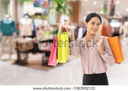 happy beautiful Asian women smile two hand holding shopping bags, copy space on shopping mall background, Annual discounted product price festival concept.