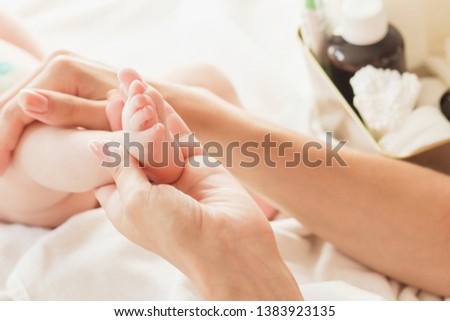 Hands of woman holds baby feet, soft focus background