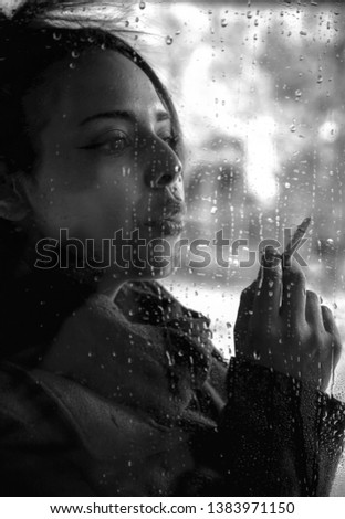 a beautiful moroccan girl is smoking a cigarette outdoors on a rainy spring day