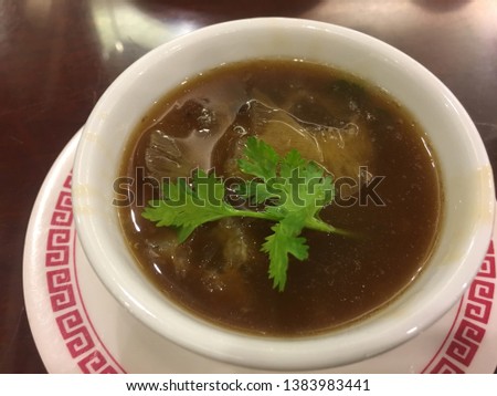 Tradition Chinese food shark fin soup on a small bowl on top with coriander serve in a restaurant.