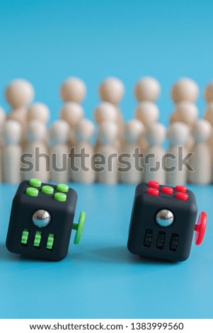 Crowd calm concept. Cube stress reliever and wooden figures on a blue background. vertical photo