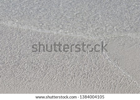 Film of transparent Caribbean water over white sand