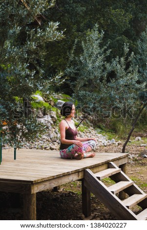 A woman practices yoga on the porch of an old wooden house. The girl goes in for sports in the yard on a warm spring day. Slender brunette doing asanas.