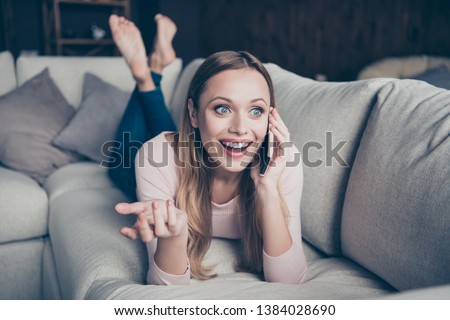Closeup photo portrait of cheerful positive cute lovely talkative with beaming toothy smile gesturing hands lying down on divan in denim trousers barefoot Royalty-Free Stock Photo #1384028690