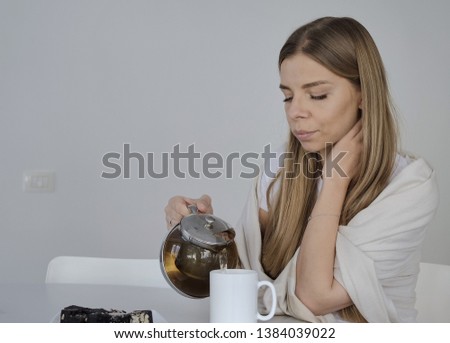 Young blond woman drinks tea in the white kitchen in good mood
