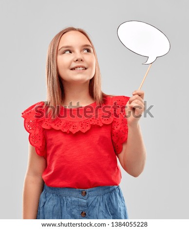 childhood and people concept - beautiful smiling girl in red shirt holding blank speech bubble over grey background