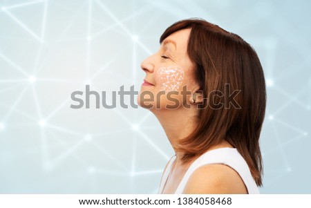 cosmetology and anti-age technology concept - profile of smiling senior woman with low poly grid on her cheek over blue background