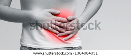 Young woman suffering from abdominal pain, holding her stomach, monochrome panorama photo Royalty-Free Stock Photo #1384084031