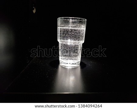 waterglass with bubbles in dark room illuminated