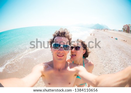 A man and a woman take a selfie. A couple is photographed on a mobile phone. Friends relax on the sea coast. Relax on the beach.
