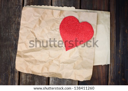 red heart on a crumpled brown paper on wooden background