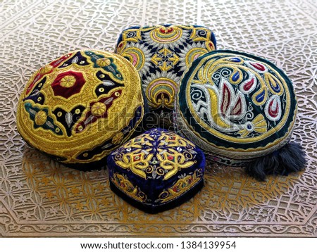 The traditional Uzbek hat, called a skullcap,or Duppi, is decorated with colorful embroidery on the table with decorative carvings.          Royalty-Free Stock Photo #1384139954