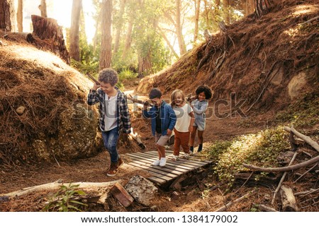 Group of children building camp in forest together. Boys and girls carrying sticks and walking Royalty-Free Stock Photo #1384179002