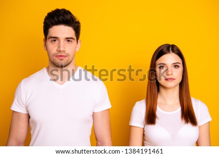 Close up photo two cool amazing beautiful she her he him his couple standing side by side not smiling look through like zombie wearing casual white t-shirts outfit clothes isolated yellow background