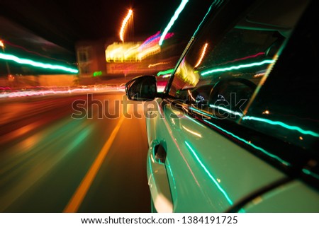 View from side of car moving in a modern night city, blurred motion with lights and cars.