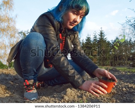 The girl is planting a young tree.