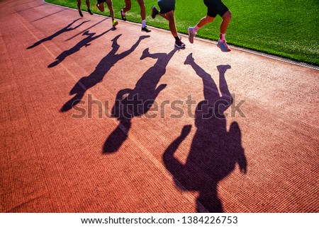 Silhouette of runners who race together in group on the athletics track. Track and Field photo