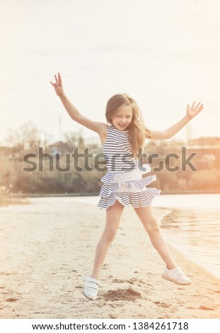 Cute little girl has a fun on the beach at sunset.