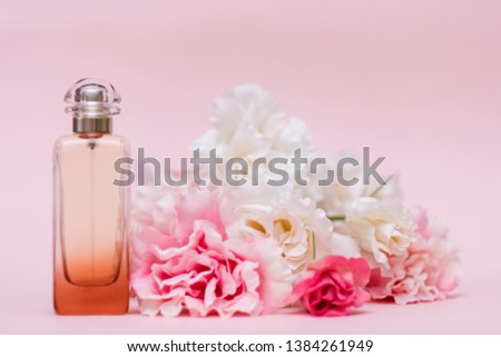 Bottle of perfume with flowers peonies on pink color background 