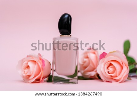 Bottle of female perfume with pink roses on pink color background