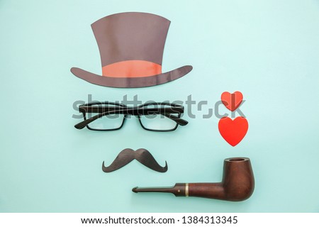 Happy Father's day concept. Sign of hat mustache with pipe glasses red heart isolated on pastel blue background. Simple minimalism flat lay top view copy space. Man silhouette symbol