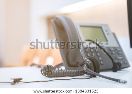 close up focus on call center headset device at telephone VOIP system at office desk for hotline telemarketing concept