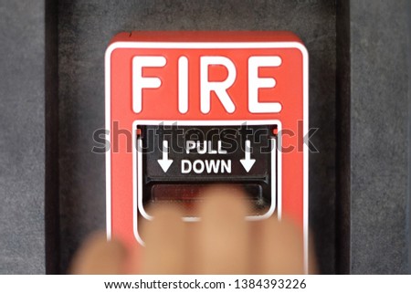 Blurry hand try to pull down for activate fire alarm system at the wall. The hand of man is pulling fire alarm on the wall. Concept warning and alert fire alarm building. Protection and emergency call
