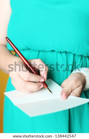 Hands writing on a white card whit dress in the background