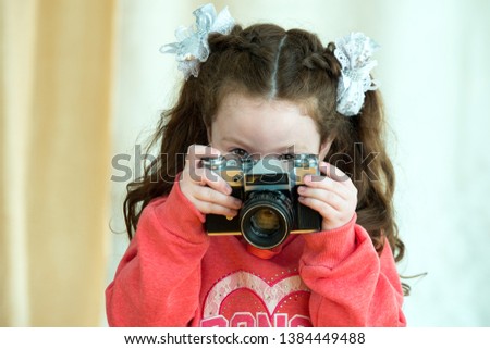 Little girl with vintage camera on light background. Cute kid girl 4-5 year old