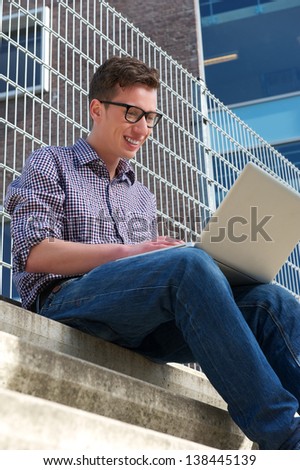 Portrait of a male college student working on laptop outdoors