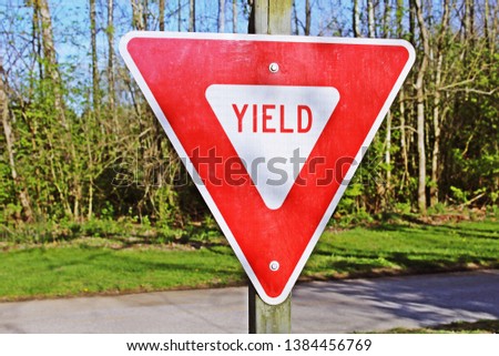 Red and white yield sign along a paved hiking trail