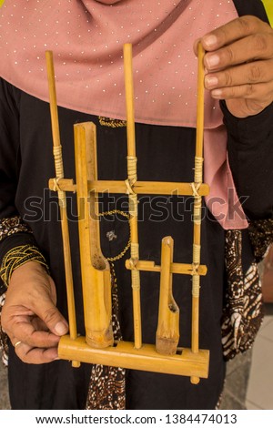Hand with the instrument Angklung is a traditional musical instrument originating from West Java, Indonesia made of bamboo