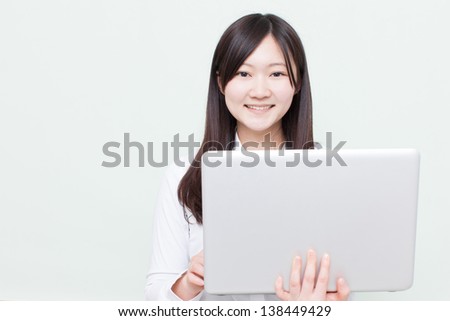 young girl using laptop computer against pale green background