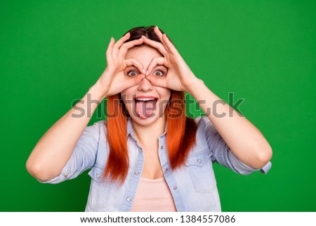 Close up photo beautiful funny she her foxy lady hold hands arms fingers okey symbol near eyes specs shape tongue out mouth playful wear casual jeans denim shirt isolated green bright background