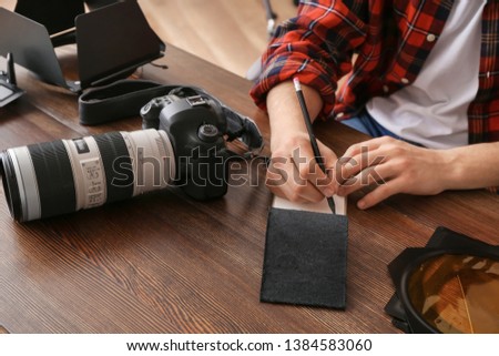 Professional photographer writing in notebook at table