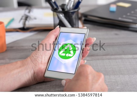 Female hand holding a smartphone with recycling concept