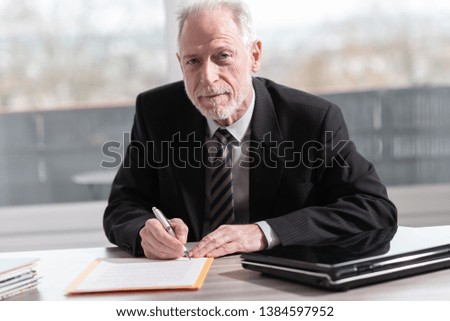 Businessman signing a document in office (Lorem ipsum text used)