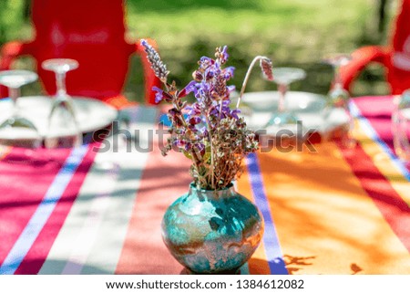 Fresh lavanda bouquet in a blue vase on a table. Beautiful tablecloth with colored lines. Perfect sunny summer day. 