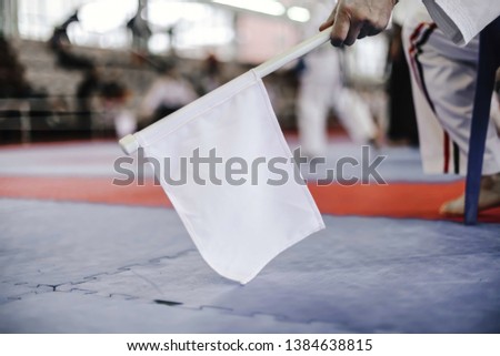 Hand of man who holds a white flag on the background of the stands