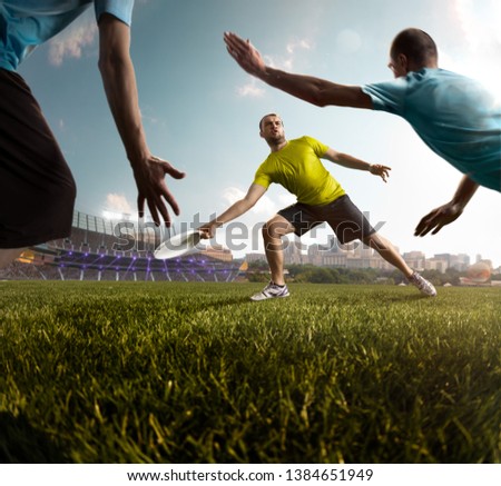 Two team play ultimate flying disc in stadium. One athlete give passes, other players bocked him. Around sunny day