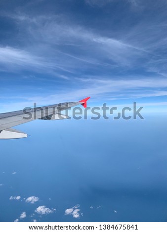 Window's perspective view from air plane which flying in the blue sky above clouds.