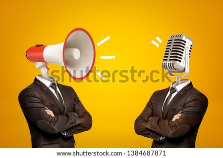Waist-deep view of two businessmen standing in half-turn, arms folded, with megaphone and microphone instead of heads. Opinion leaders. Media influence public opinion. Media and people. Royalty-Free Stock Photo #1384687871