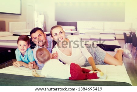 Smiling british  parents with two young sons testing mattress in store