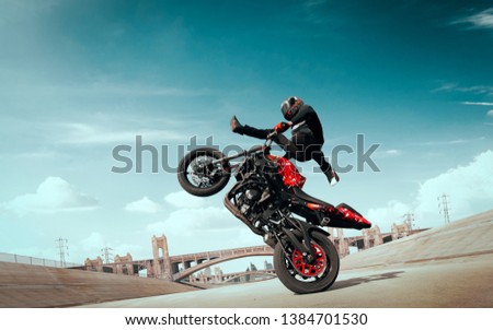 Moto rider making a stunt on his motorbike. Biker doing a difficult and dangerous stunt. Royalty-Free Stock Photo #1384701530
