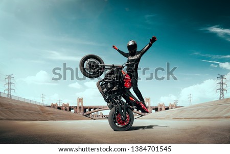Moto rider making a stunt on his motorbike. Biker doing a difficult and dangerous stunt. Royalty-Free Stock Photo #1384701545